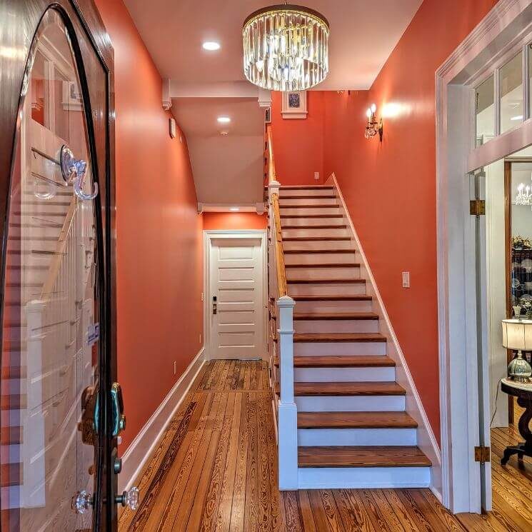 A foyer with peach colored walls, white trim, and a wood and white trimmed staircase