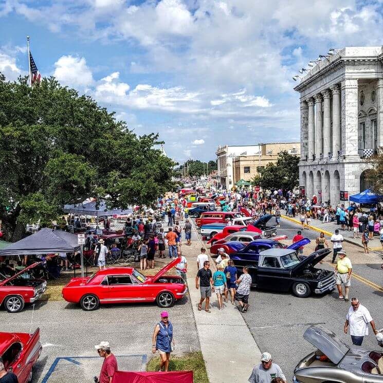 A street lined with antique cars for a car show, lined with dozens of onlookers